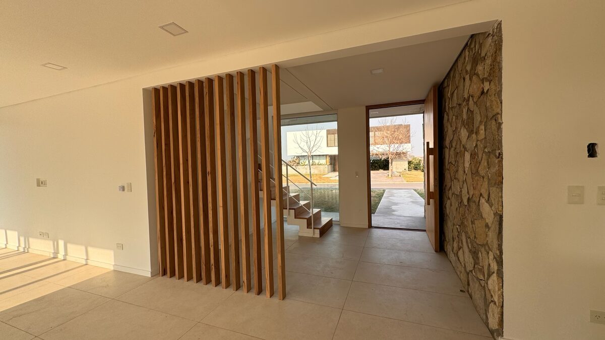 Hall de acceso terminado, con tabique de listones de madera y muro de piedra.